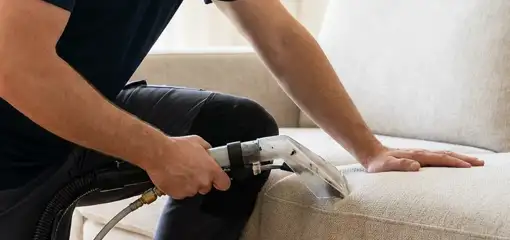 Professional upholstery cleaner deep-cleaning a fabric sofa with a handheld extraction tool, Oakland, CA.